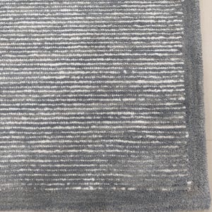 May include: A close-up of a gray and white striped rug with a gray border. The rug has a soft, textured feel.