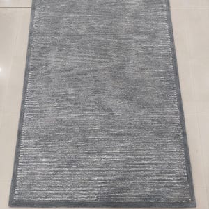 May include: A gray area rug with a subtle white stripe pattern. The rug has a soft, plush texture.