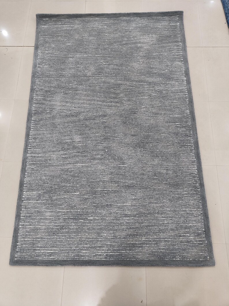 May include: A gray area rug with a subtle white stripe pattern. The rug has a soft, plush texture.