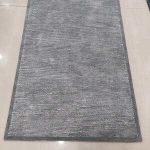 May include: A gray area rug with a subtle striped pattern. The rug has a soft, plush texture and a contemporary design.