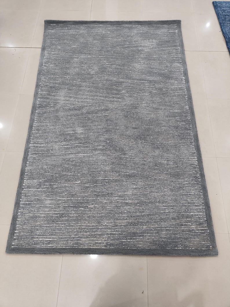 May include: A gray area rug with a subtle striped pattern. The rug has a soft, plush texture and a contemporary design.