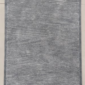 May include: A gray area rug with a subtle white stripe pattern. The rug has a soft, textured surface.