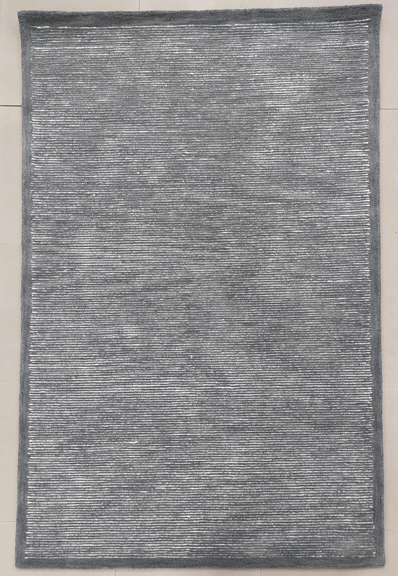 May include: A gray area rug with a subtle white stripe pattern. The rug has a soft, textured surface.