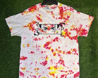 May include: A white t-shirt with a red and yellow tie-dye pattern. The shirt features a black and white illustration of a character's eyes with a decorative border. The text "Cosmos Designs" is printed on the bottom right corner of the shirt.