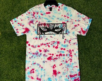 May include: A white tie-dye t-shirt with a black and white anime-style illustration of a character's eye and forehead. The text "Comic Designs" is visible in the bottom right corner.