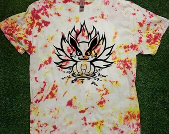 May include: White t-shirt with a tie-dye pattern in red and yellow. The shirt features a black graphic of a cartoon fox with a flame-like design behind it. The text "Cosmos Design" is printed on the bottom right.