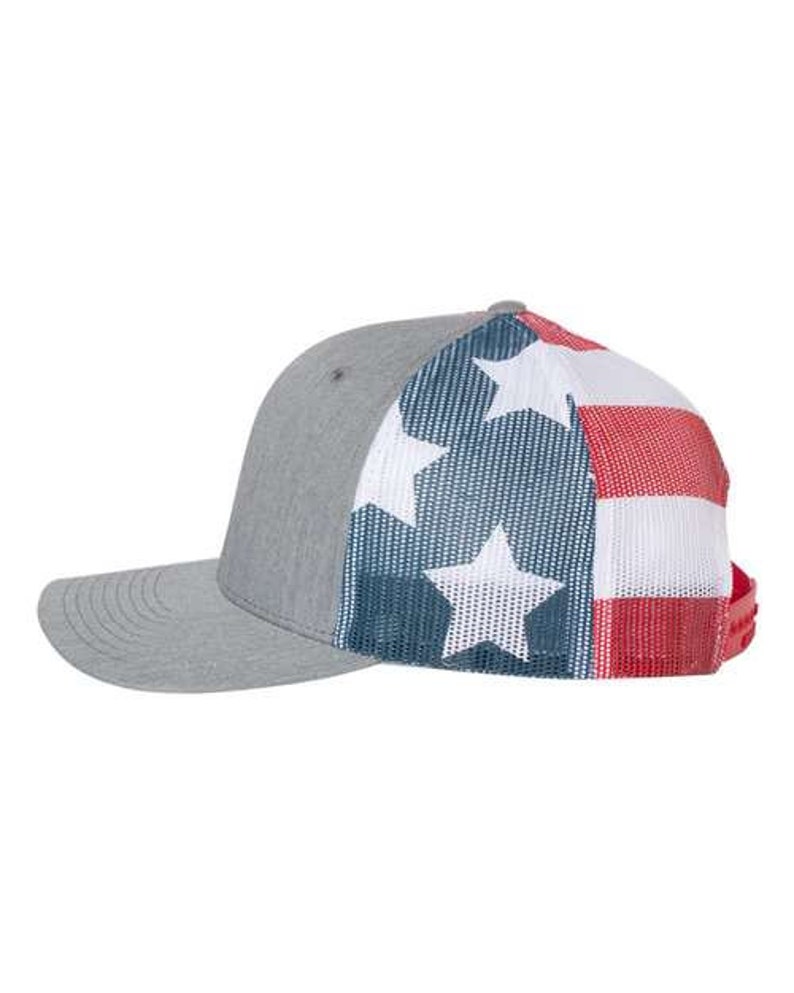 May include: A gray and white trucker hat with a red, white, and blue American flag design on the back. The hat has a mesh back and a curved brim.