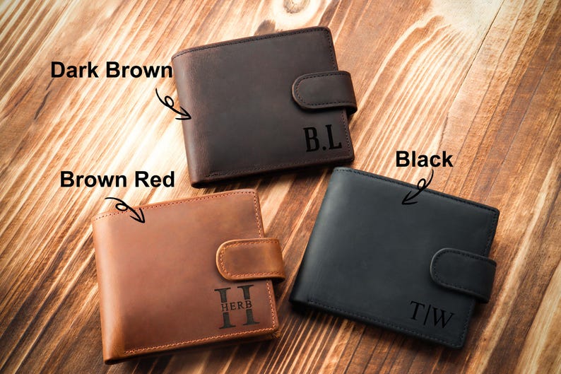 Puede incluir: Tres carteras de cuero en diferentes colores: marr&oacute;n oscuro, marr&oacute;n rojizo y negro. Cada cartera tiene un cierre de solapa con un monograma personalizado.