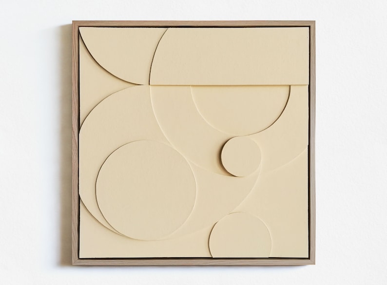 May include: A framed beige canvas with a geometric design of overlapping circles and semi-circles.