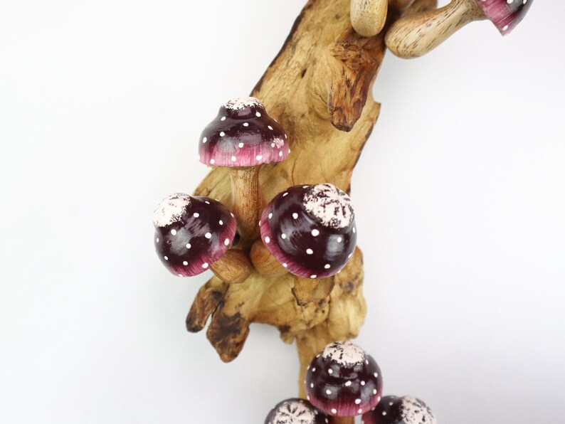 Pu&ograve; includere: Un gruppo di funghi in legno fatti a mano, con cappelli bordeaux e pois bianchi, attaccati a un ramo di legno naturale. Questi funghi decorativi sono ideali per l'arredamento d'interni.