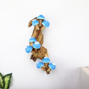 Pu&ograve; includere: Scultura in legno raffigurante funghi blu con pois bianchi. I funghi sono attaccati a un pezzo di legno naturale, creando un pezzo stravagante e decorativo. La scultura &egrave; posta su uno sfondo bianco.