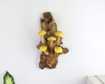 May include: A wooden wall decoration featuring a piece of driftwood with five yellow mushrooms with white polka dots attached to it.
