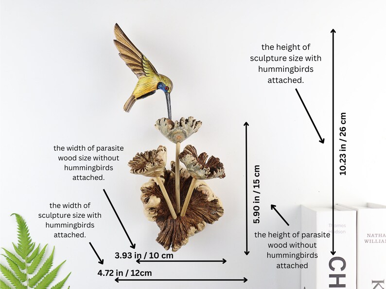K&ouml;nnte beinhalten: Holzskulptur eines Kolibris mit gelb-braunem K&ouml;rper &uuml;ber stilisierten Blumen. Die Skulptur ist auf Parasitenholz montiert. Die Skulptur ist 26 cm hoch und 12 cm breit.