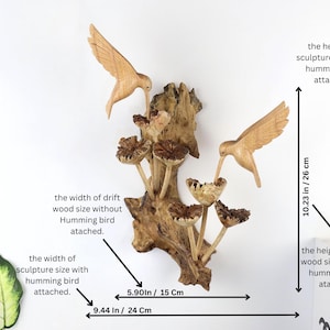 May include: Wooden sculpture featuring two carved hummingbirds and stylized mushrooms, attached to a piece of driftwood. The sculpture is 13.38 inches (34 cm) tall and 9.44 inches (24 cm) wide.