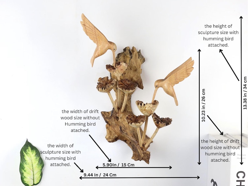 May include: Wooden sculpture featuring two carved hummingbirds and stylized mushrooms, attached to a piece of driftwood. The sculpture is 13.38 inches (34 cm) tall and 9.44 inches (24 cm) wide.