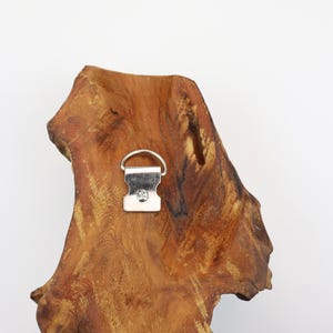 May include: A piece of natural wood with a metal hanger attached. The wood has a rich brown color with a unique, organic shape. The metal hanger is silver and designed for wall mounting.