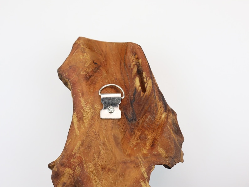 May include: A piece of natural wood with a metal hanger attached. The wood has a rich brown color with a unique, organic shape. The metal hanger is silver and designed for wall mounting.