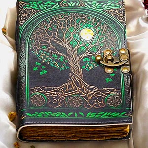 Puede incluir: Un diario de cuero negro con un diseño de árbol de la vida. La cubierta presenta un diseño detallado de árbol en verde y dorado, con una luna llena. Tiene un cierre de metal y páginas envejecidas. El diseño del diario sugiere una estética vintage.
