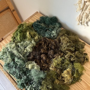 May include: A collection of different shades of green and brown wool fibers, perfect for crafting and textile projects.