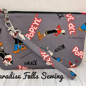 Cartera con correa para la muñeca y cierre de cremallera con anilla en D y ranuras para tarjetas de tela exclusiva de Popeye Olive Oyl de Paradise Falls Sewing