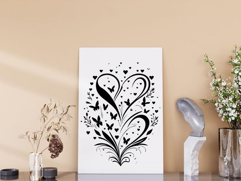 Puede incluir: Impresi&oacute;n en blanco y negro de una forma de coraz&oacute;n estilizada con mariposas y corazones. El dise&ntilde;o recuerda a un patr&oacute;n floral.