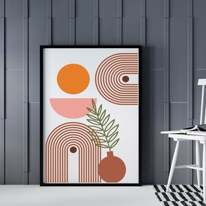 May include: A framed print with an abstract design featuring a pink and orange circle, a brown and white striped arch, and a green leaf with a brown vase. The background is white.