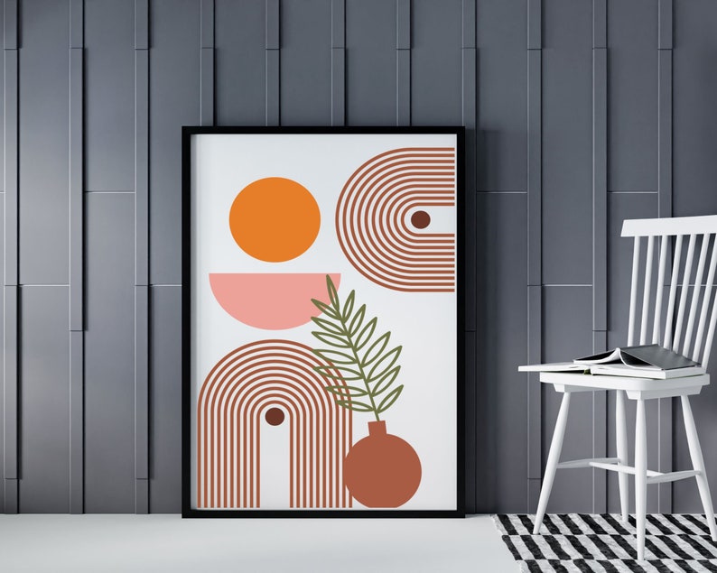 May include: A framed print with an abstract design featuring a pink and orange circle, a brown and white striped arch, and a green leaf with a brown vase. The background is white.