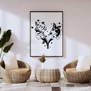 Puede incluir: Dos sillas de mimbre con cojines blancos se enfrentan en un sal&oacute;n. Una mesa de centro de mimbre se encuentra entre las sillas. Una impresi&oacute;n en blanco y negro enmarcada de una mariposa y corazones cuelga de la pared detr&aacute;s de la mesa de centro. Una planta en maceta se encuentra en el suelo a la izquierda de las sillas.