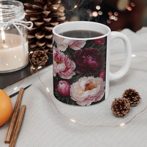 Könnte beinhalten: Ein Set aus drei Keramikbechern mit gesprenkelter, matter Oberfläche. Die Becher sind in Creme-, Hellgrau- und Dunkelgrautönen gehalten. Jeder Becher hat ein schlichtes, minimalistisches Design.