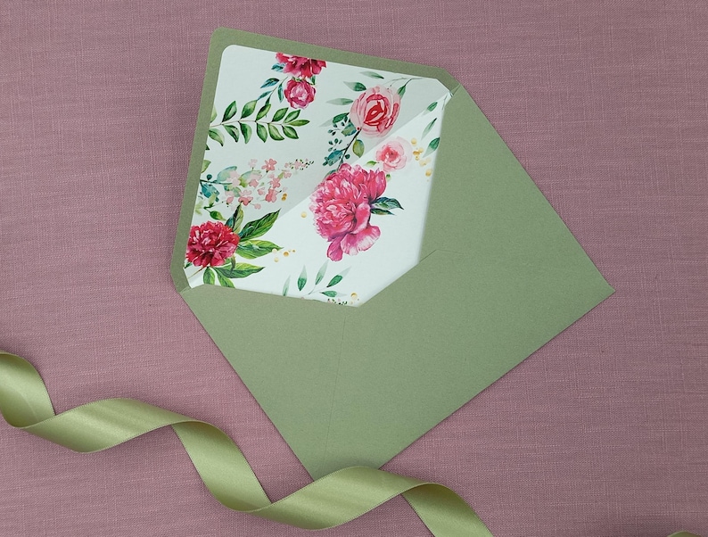 May include: A green envelope with a floral design on the inside flap. The flowers are pink and red with green leaves.