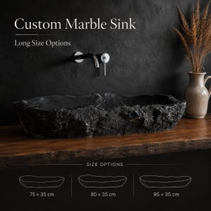 Puede incluir: Un lavabo de mármol negro personalizado con un diseño texturizado y naturalista. El lavabo se muestra con un grifo de pared y opciones de tamaño: 75 x 35 cm, 80 x 35 cm y 95 x 35 cm. El texto "Custom Marble Sink" y "Long Size Options" son visibles.