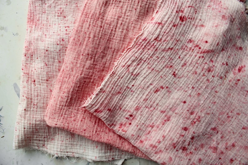 Puede incluir: Tres piezas de tela rosa y blanca con un patr&oacute;n moteado. La tela est&aacute; doblada y superpuesta, mostrando diferentes tonos de rosa.