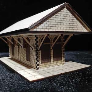 May include: A miniature wooden model of a train station with a brick facade and a tiled roof. The station has arched windows and is numbered 1, 2, and 3. The base is a tiled platform.