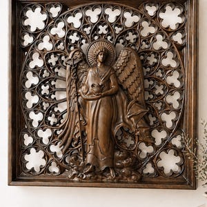 May include: A dark brown wooden wall art piece featuring a carved angel figure with wings, a halo, and a staff. The angel is set against an openwork background with a repeating floral pattern, all within a rectangular frame. The artwork is a decorative piece.