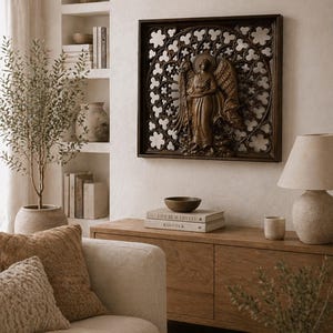 May include: A brown wooden wall art piece featuring an angel sculpture within a decorative frame. The angel has detailed wings and is set against a patterned background. The artwork hangs above a wooden cabinet in a living room setting.