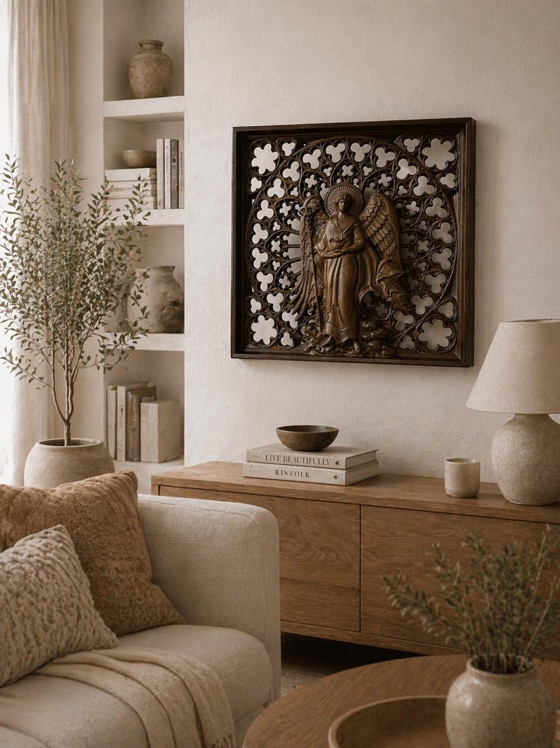 May include: A brown wooden wall art piece featuring an angel sculpture within a decorative frame. The angel has detailed wings and is set against a patterned background. The artwork hangs above a wooden cabinet in a living room setting.