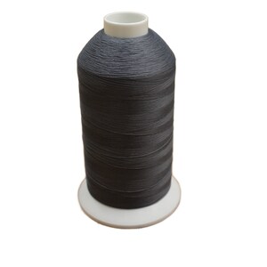 May include: A spool of dark grey thread on a white bobbin.