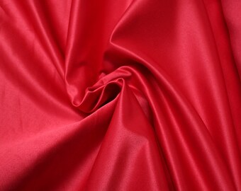May include: A close-up of a smooth, red satin fabric with soft folds and wrinkles.