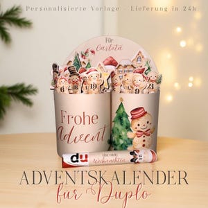 Puede incluir: Un calendario de Adviento personalizado para Duplo, con dos recipientes cilíndricos decorados con hombres de jengibre y adornos de árboles de Navidad. El texto "Frohe Advent" es visible. El calendario es para Carlota.