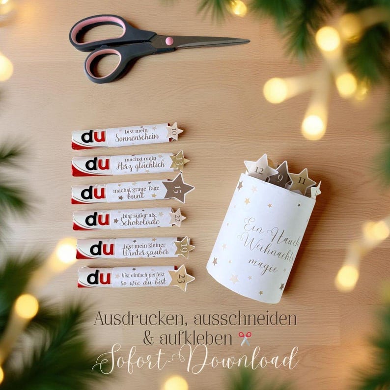 Op de afbeelding: Een feestelijke opstelling met een schaar, chocoladerepen met Duitse tekst en een witte container met gouden sterren en tekst. De sc&egrave;ne speelt zich af op een houten oppervlak, met decoratieve lichten en groen.