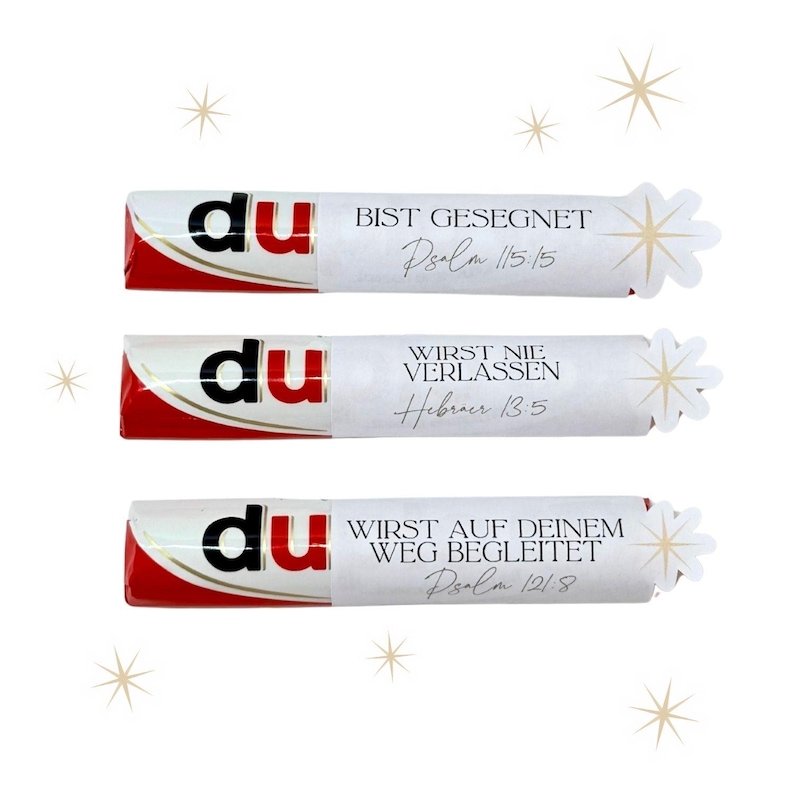 May include: Three chocolate bars with white wrappers and red accents. Each wrapper has the word "du" in black, and a different German phrase with a Bible verse reference. Decorative starbursts are on the right.
