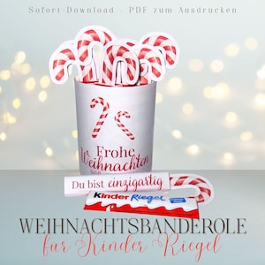 May include: A festive Christmas-themed image featuring a white cup filled with candy cane cutouts. The cup has red candy cane designs and the words "Frohe Weihnachten" and "Du bist einzigartig". A Kinder Riegel candy bar is also visible.