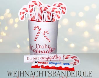 May include: A festive Christmas-themed image featuring a white cup filled with candy cane cutouts. The cup has red candy cane designs and the words "Frohe Weihnachten" and "Du bist einzigartig". A Kinder Riegel candy bar is also visible.