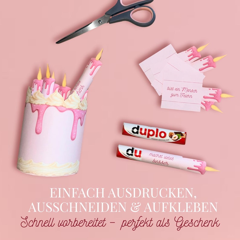 May include: A pink birthday cake-shaped gift box with dripping pink frosting and yellow candle flames. The image includes scissors, Duplo candy bars, and small cards with text. The text on the image says "Einfach ausdrucken, ausschneiden & aufkleben".