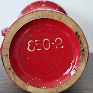 May include: Red ceramic vase with white polka dots and the number "E50-2" printed on the bottom.