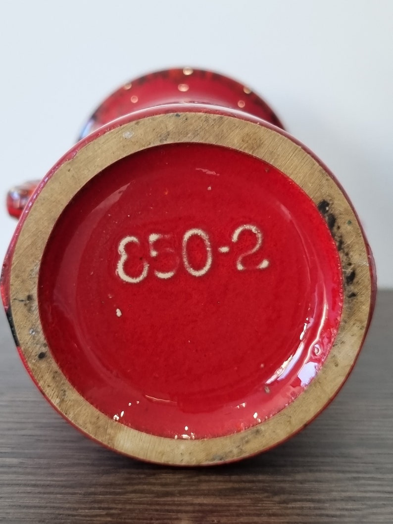 May include: Red ceramic vase with white polka dots and the number "E50-2" printed on the bottom.