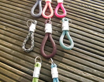 May include: Assortment of colourful rope keychains with silver metal rings. The keychains are made of braided rope in various colours, including teal, green, pink, and grey.