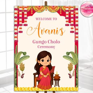 May include: A welcome sign for "Avani's Gungo Cholo Ceremony" features a cartoon illustration of a girl in a red sari. The sign has a cream background with red and gold decorative borders and floral accents. The sign is displayed on an easel.