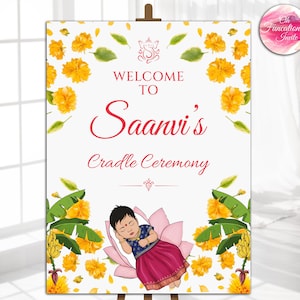Puede incluir: Un letrero de bienvenida para la ceremonia de la cuna de Saanvi. El letrero presenta a un bebé durmiendo sobre una flor de loto, rodeado de flores amarillas y hojas verdes. El texto es rojo y el fondo es blanco.