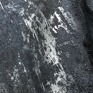 Puede incluir: Primer plano de una superficie texturizada de color gris oscuro con una veta metálica plateada que recorre la superficie en diagonal.